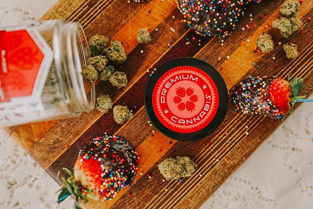Premium cannabis flower next to chocolate-covered strawberries and jar