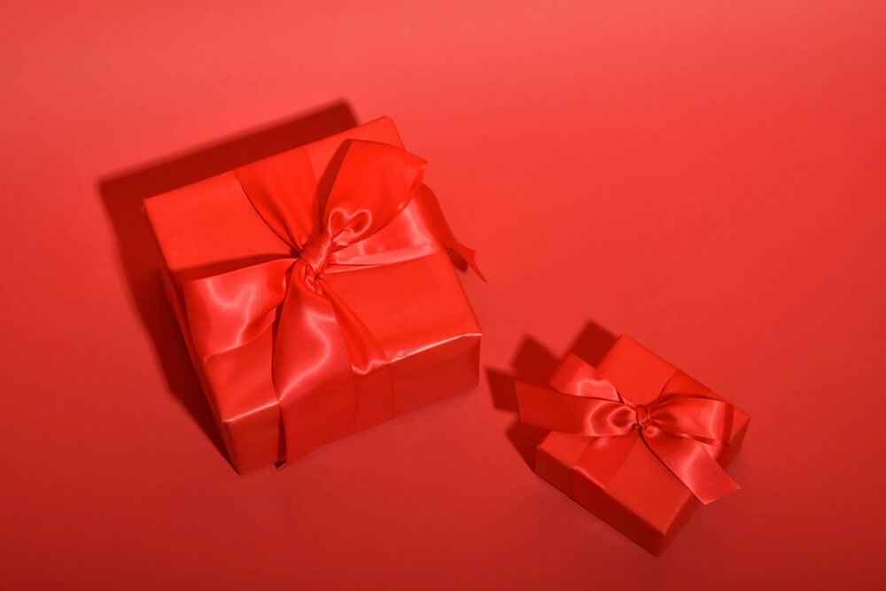 Matching red gift boxes with red satin ribbon on red background
