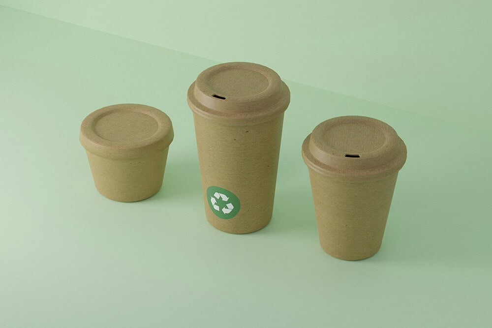 Compostable paper coffee cups with green recycling icon