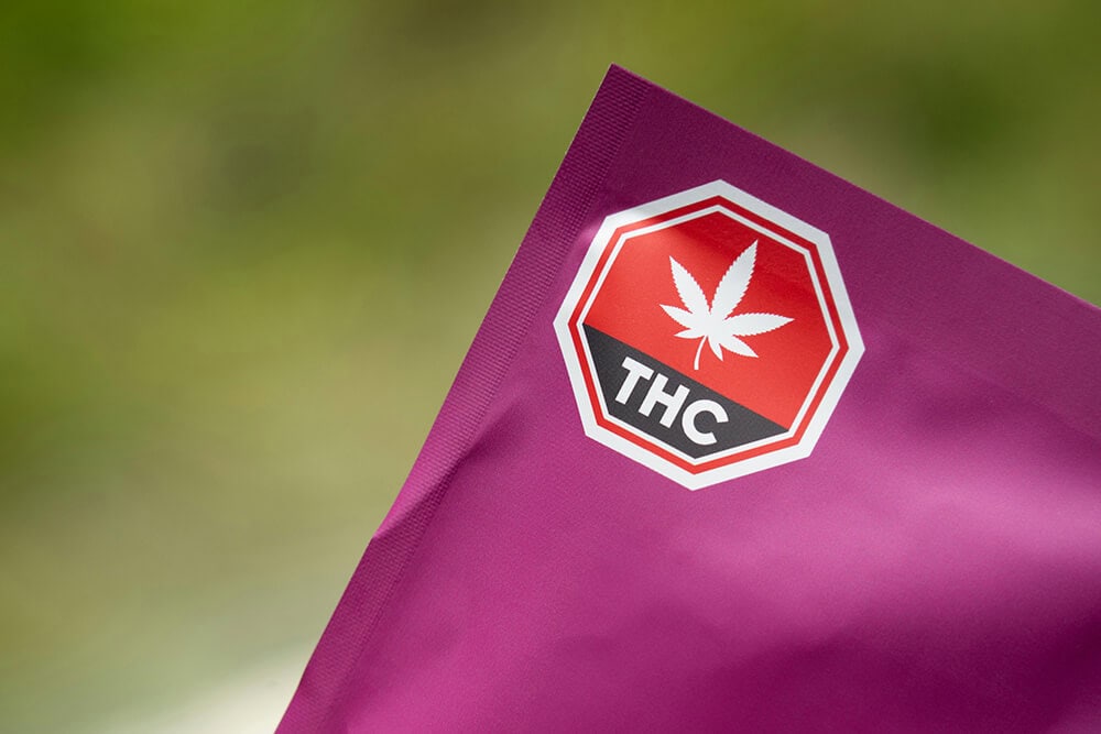 Close-up of THC warning label on magenta cannabis pouch