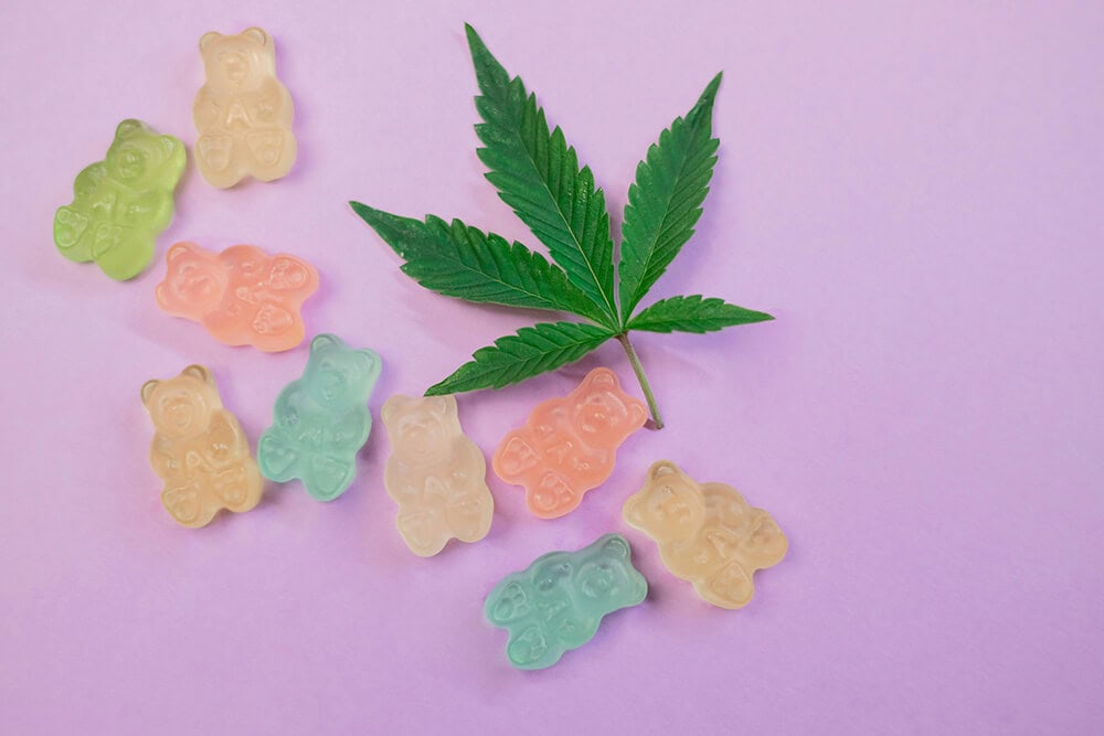 Gummy bears with cannabis leaf on pink background
