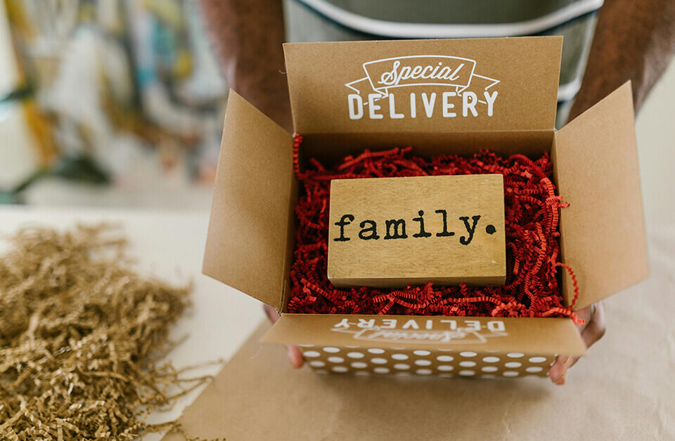 Kraft gift boxes labeled “Special Delivery” with red filler and a wooden “family” block inside