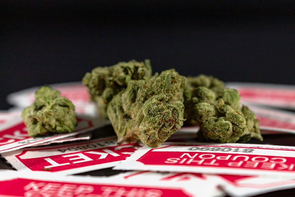 Close-up of cannabis buds on top of red ticket coupons