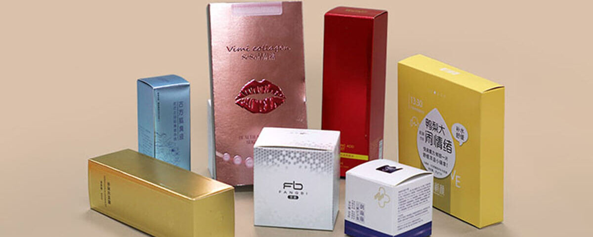 Assorted metallic paper printing cosmetic boxes in gold, silver, red, pink, and yellow finishes.