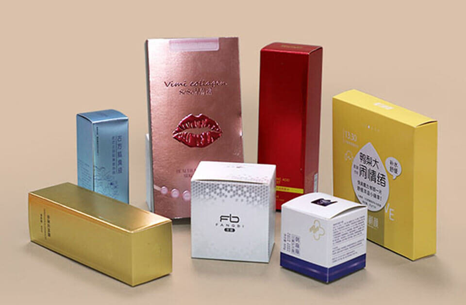 Assorted metallic paper printing cosmetic boxes in gold, silver, red, pink, and yellow finishes.