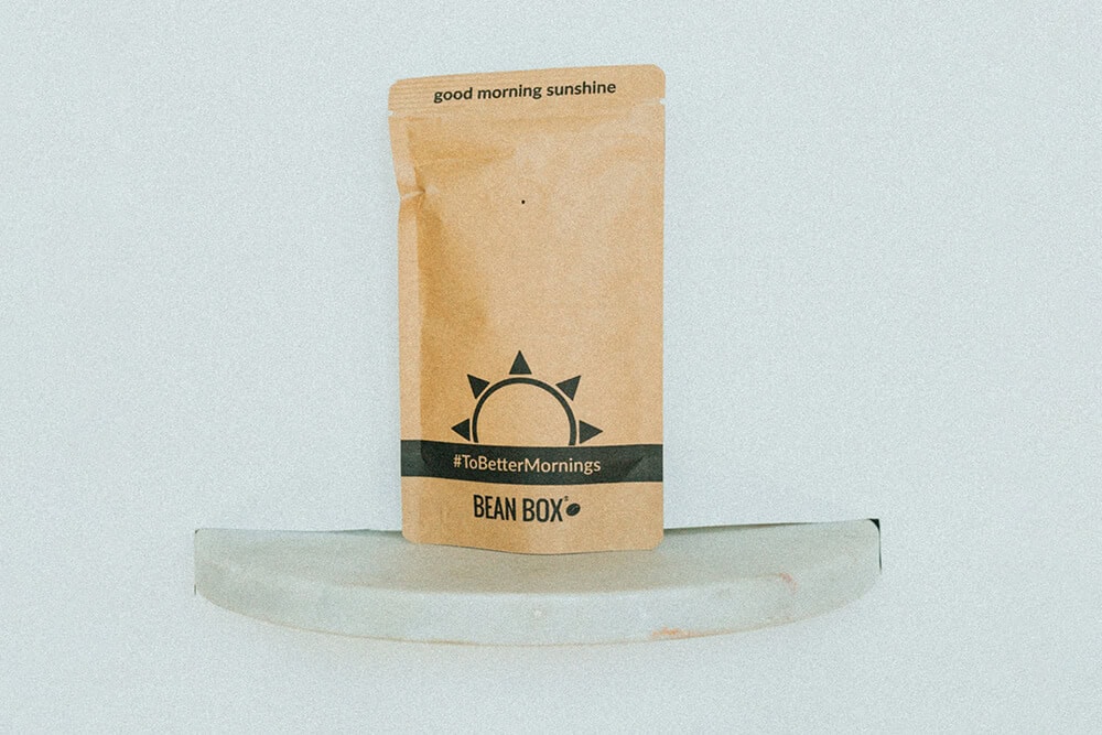 Brown stand-up pouch with black sun graphic and text “Good Morning Sunshine” from Bean Box.
