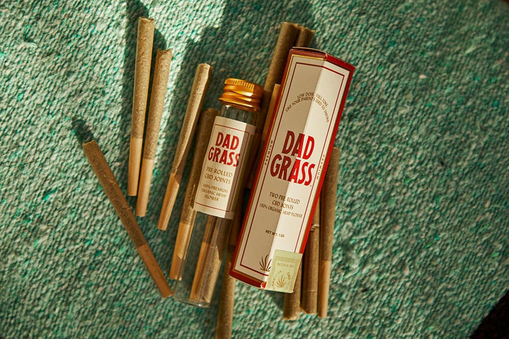 Multiple Dad Grass pre rolled blunts and packaging on textured green background