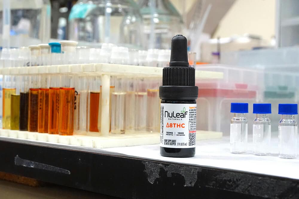 Delta 8 THC tincture bottle on a lab counter surrounded by vials and test tubes
