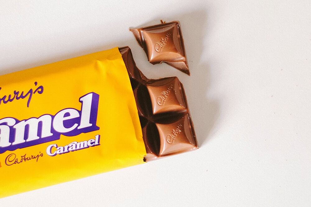 Partially opened Cadbury caramel chocolate bar with rich chocolate squares