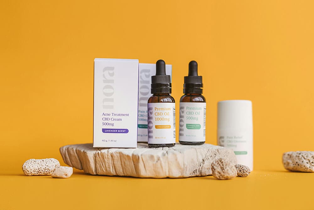 CBD oil tinctures and skincare cream in minimalist packaging on yellow backdrop