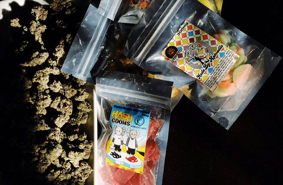 ssorted cannabis edibles with custom weed stickers and marijuana buds on a dark surface.