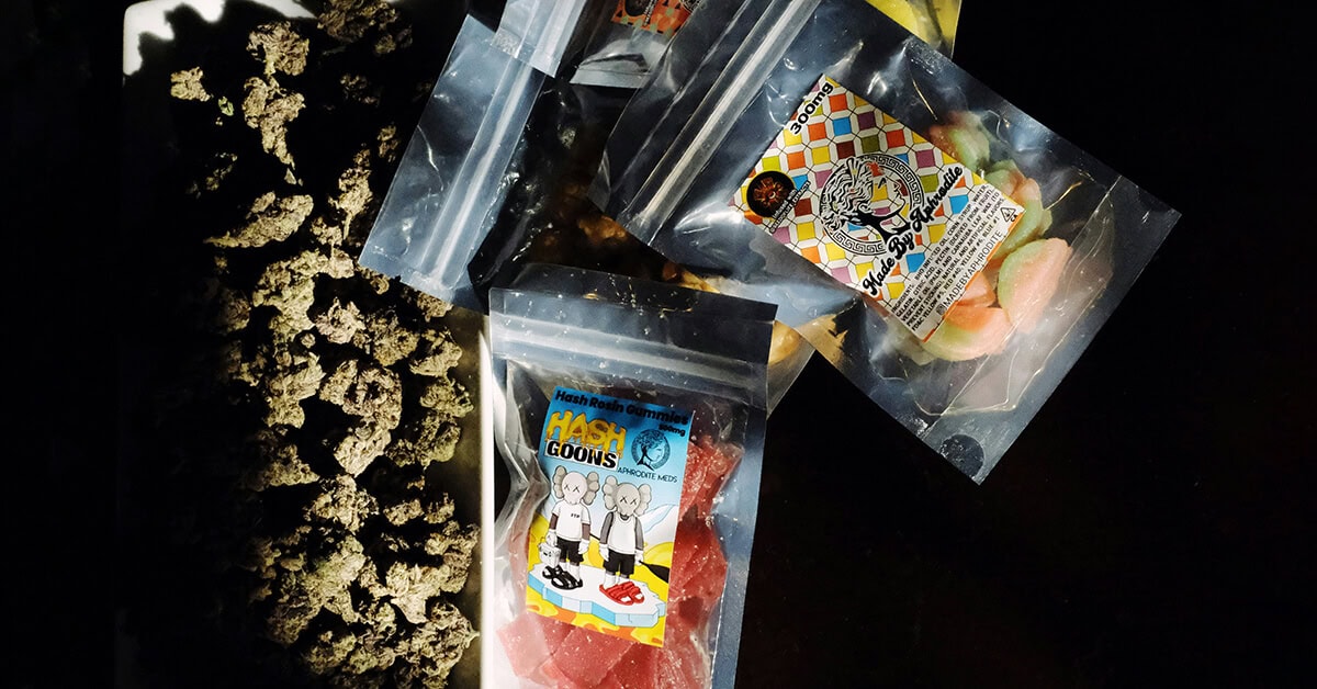 ssorted cannabis edibles with custom weed stickers and marijuana buds on a dark surface.