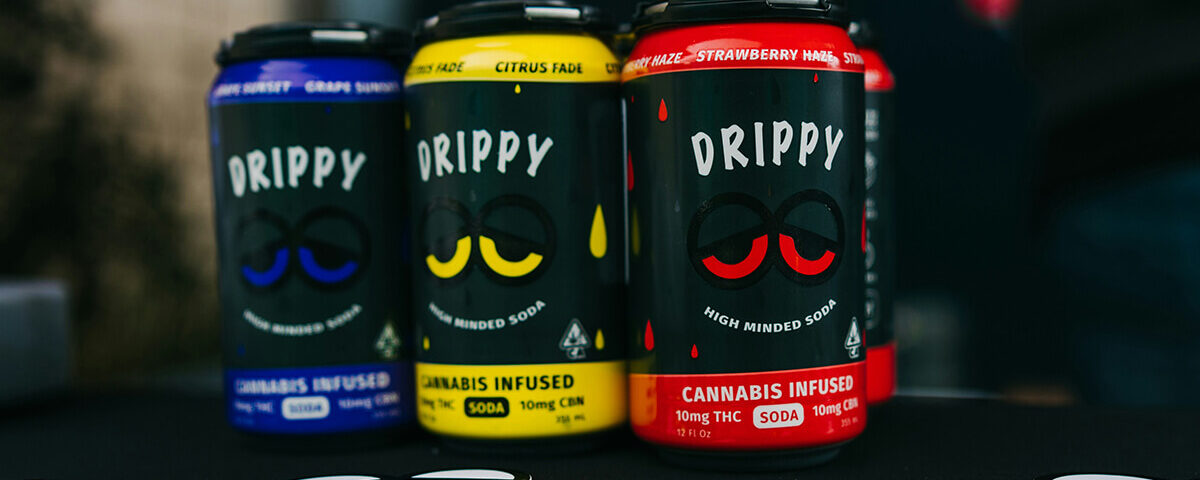Three cans of Drippy cannabis beverage soda in grape, citrus, and strawberry flavors.
