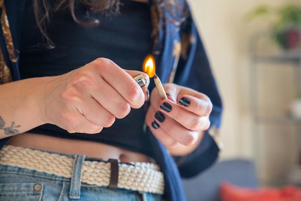 Close-up of hands lighting a mini blunt with a lighter.