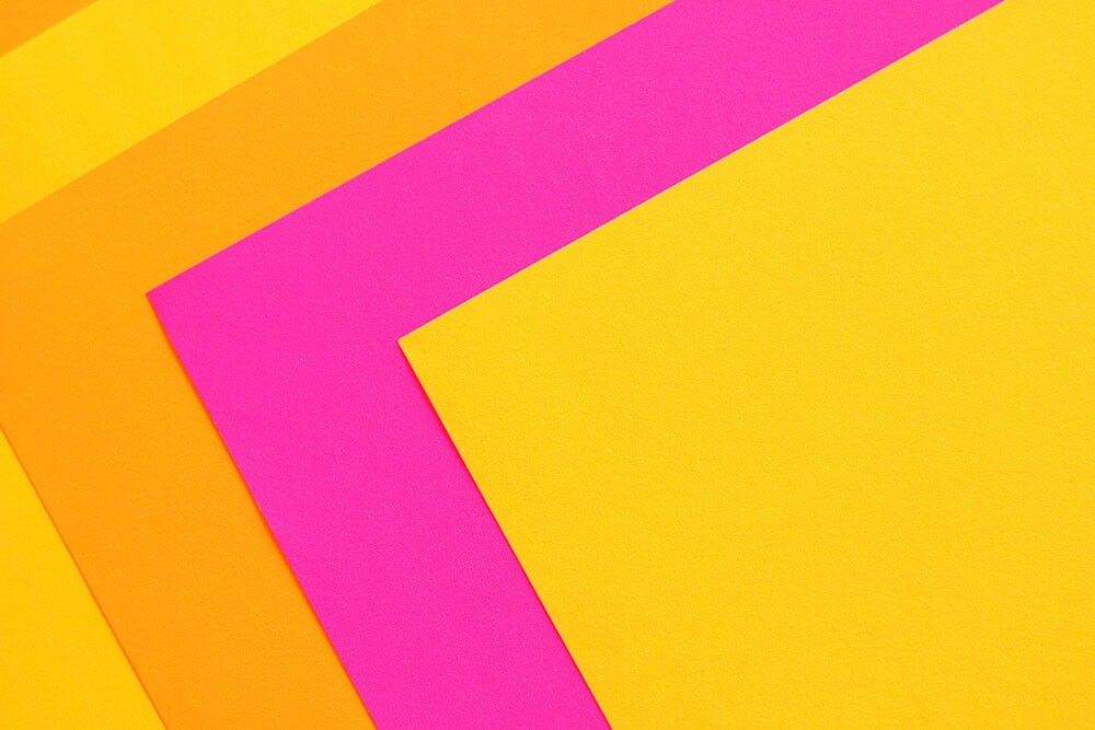 Bright paper sheets in yellow, pink, and orange for printing projects