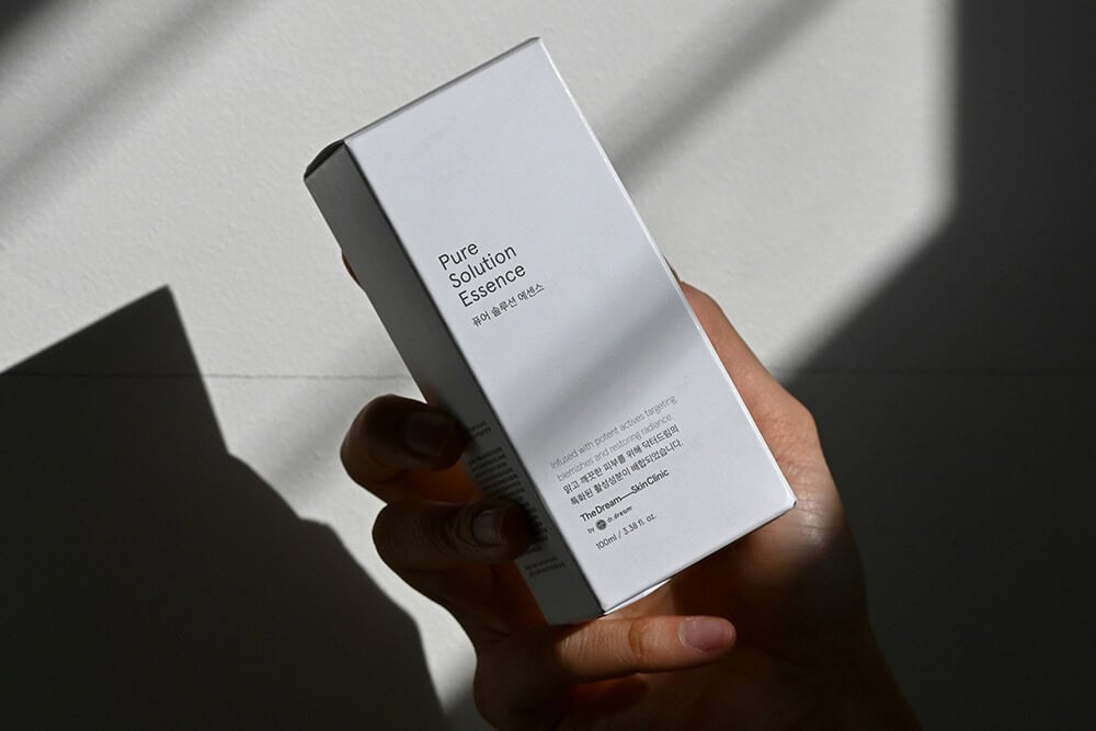 Pure Solution Essence skincare packaging with minimalistic white design.
