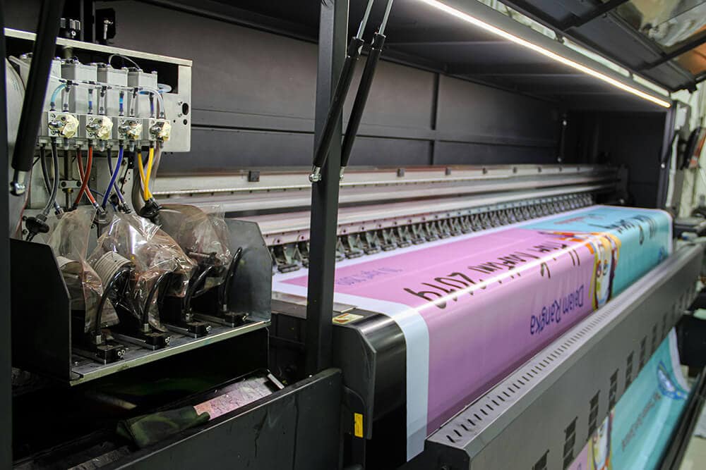 Large format digital printing machine creating colorful banners and packaging designs.