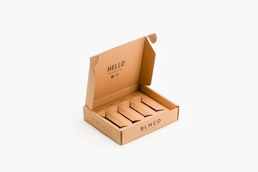 Open kraft mailer box with multiple custom-cut cardboard inserts for product display.