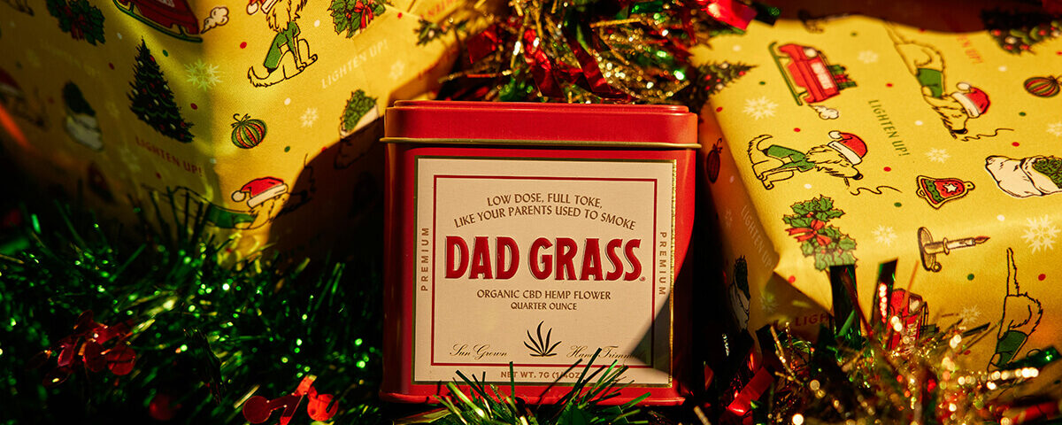 holiday packaging ideas: Holiday-themed CBD tin surrounded by festive wrapping paper and Christmas decorations.