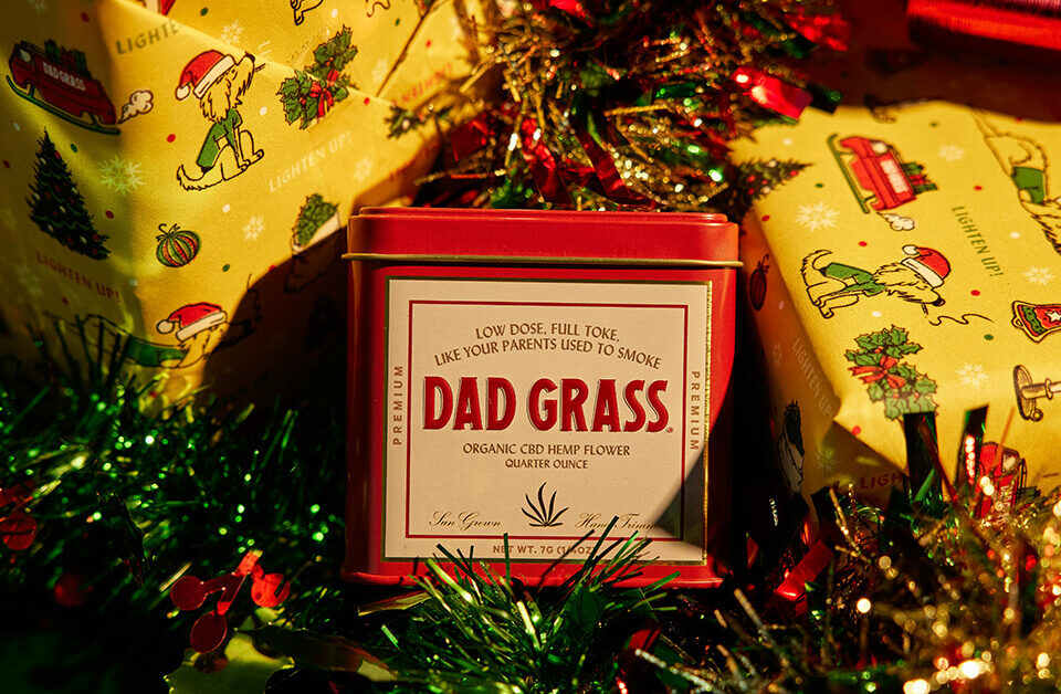 holiday packaging ideas: Holiday-themed CBD tin surrounded by festive wrapping paper and Christmas decorations.