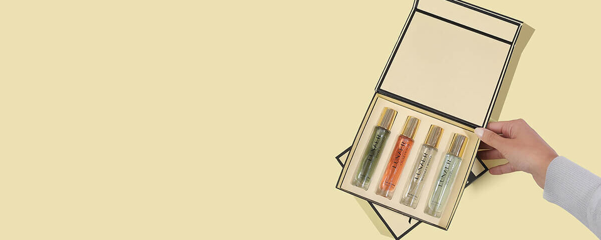 Luxury rigid box for perfume set with custom insert and gold-cap bottles being opened.