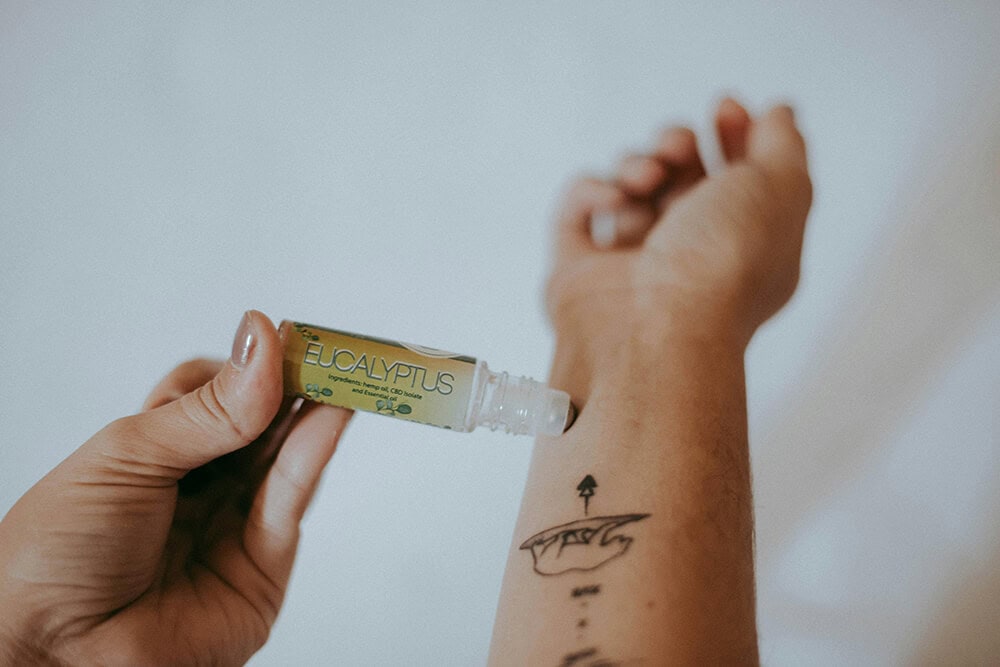 A person applying a CBD relief stick infused with eucalyptus to the skin for targeted pain relief.
