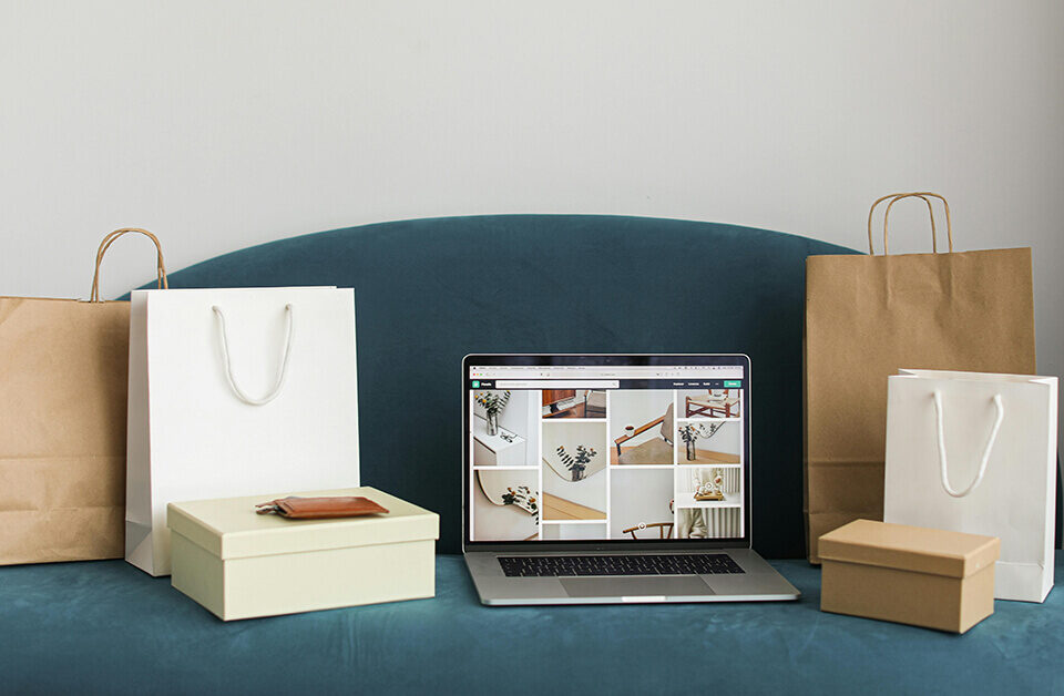 E-commerce packaging options with paper bags and boxes beside a laptop showing product photos.