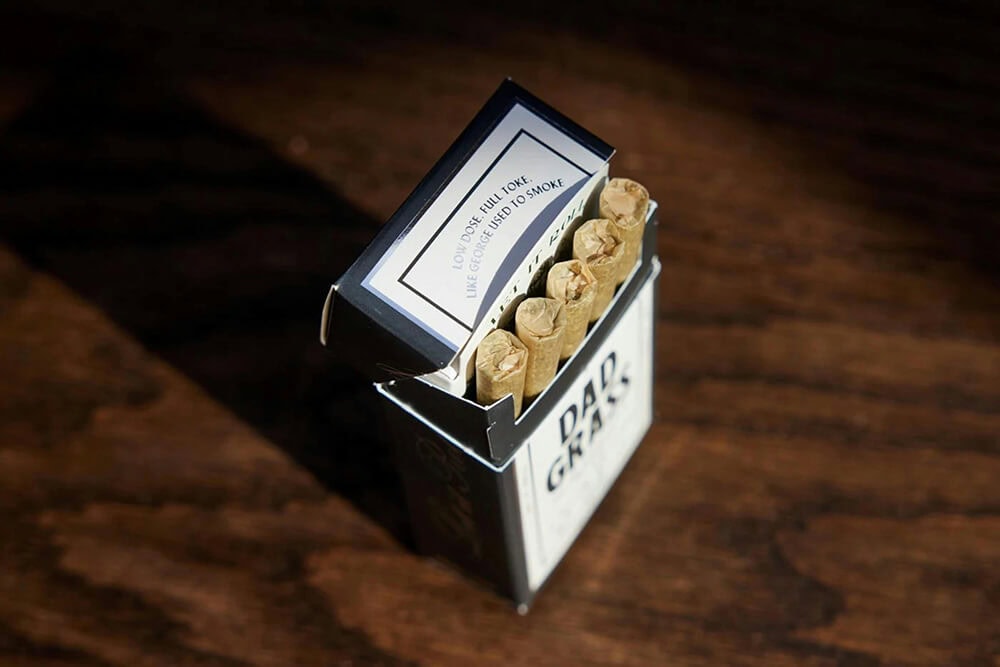 Open Dad Grass folding box revealing tightly packed pre-rolls inside premium cannabis packaging.