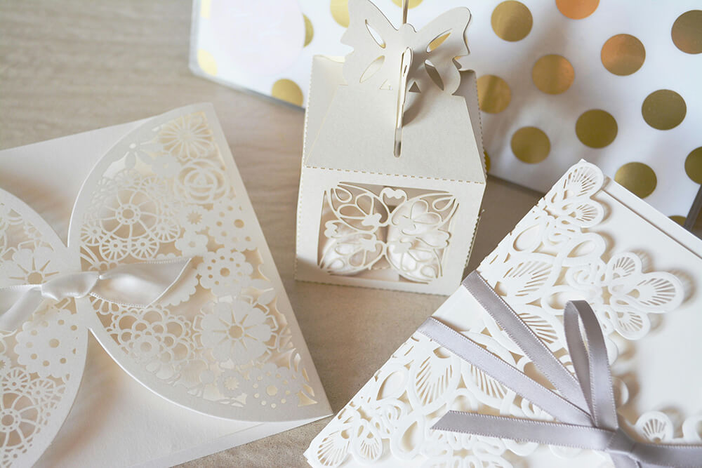 Delicate white laser-cut gift boxes and cards with floral designs and ribbons.