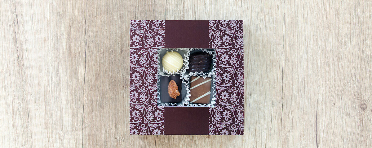 Top view of custom chocolate gift boxes with a floral pattern and a clear square window showing four truffles.