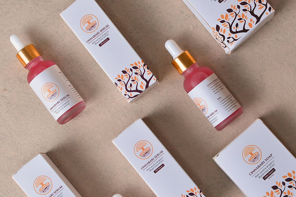 White folding cartons with botanical illustrations next to red serum bottles, representing consistent branding in luxury boxes packaging.