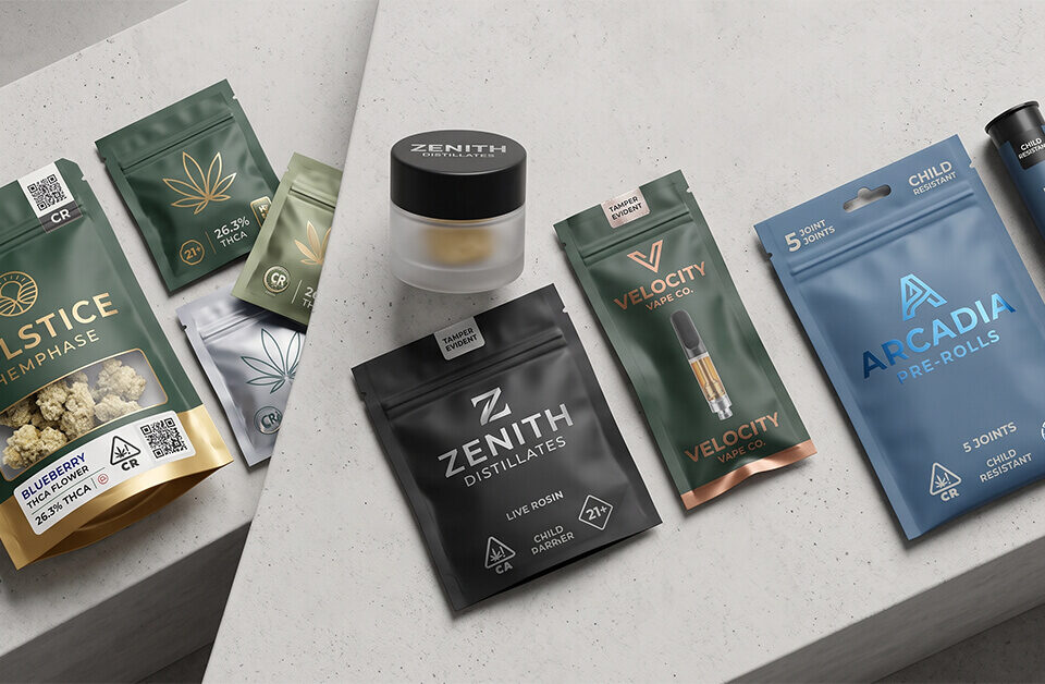 Flat lay of premium custom cannabis THCA packaging including flower bags, a concentrate jar, vape cartridges, and pre-roll packs on concrete display blocks.